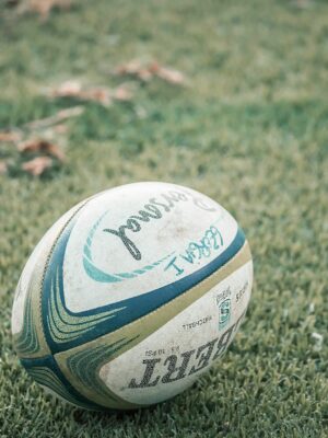 A close-up shot of a rugby ball resting on a grass field, ideal for sports theme.
