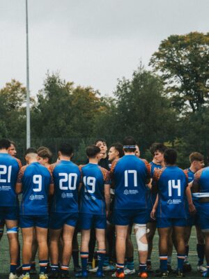A rugby team in blue jerseys huddled together on a field, showcasing teamwork and strategy.