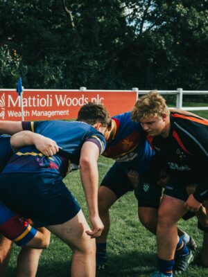 Players engage in a fierce rugby scrum during an outdoor match on a sunny day.